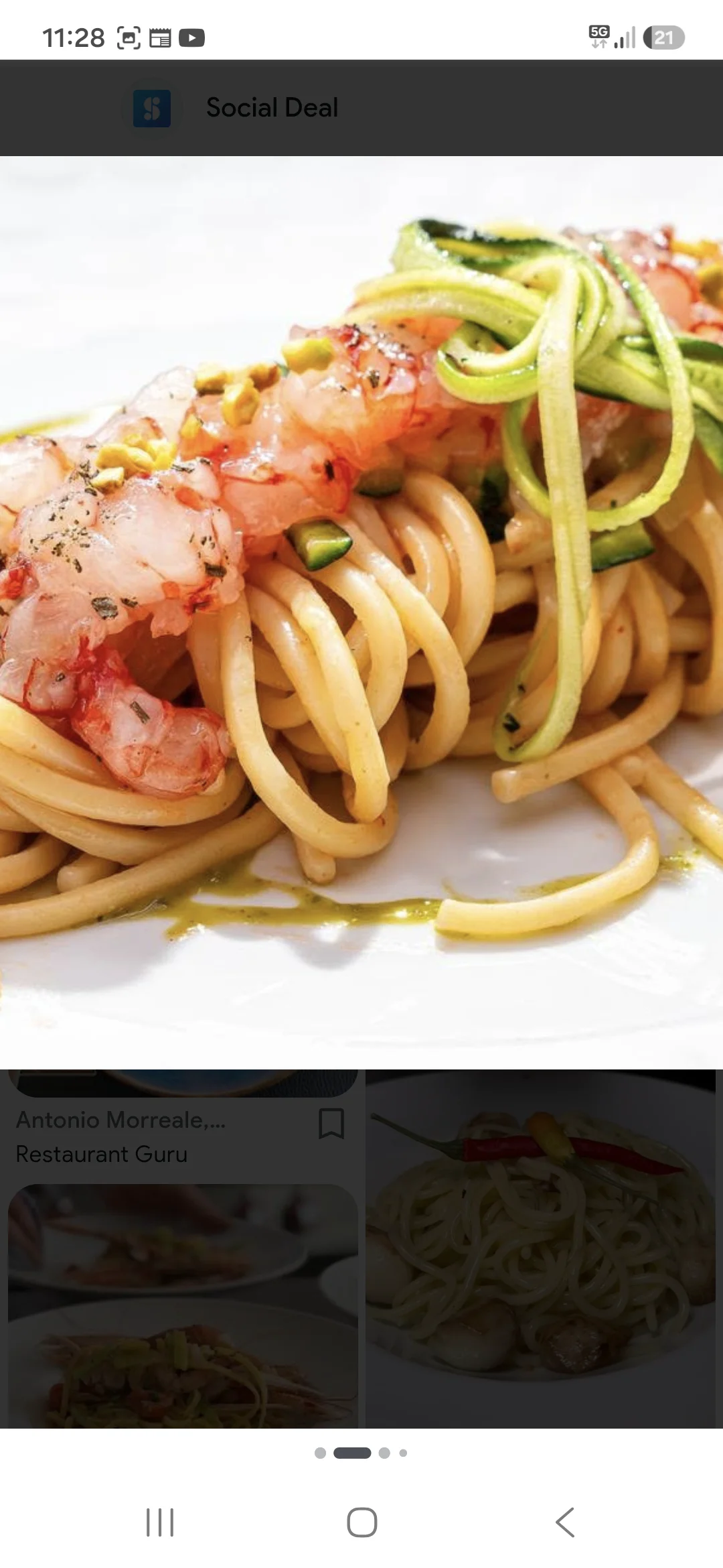 Assiette de pâtes longues avec crevettes, rubans de courgette et petits morceaux colorés.